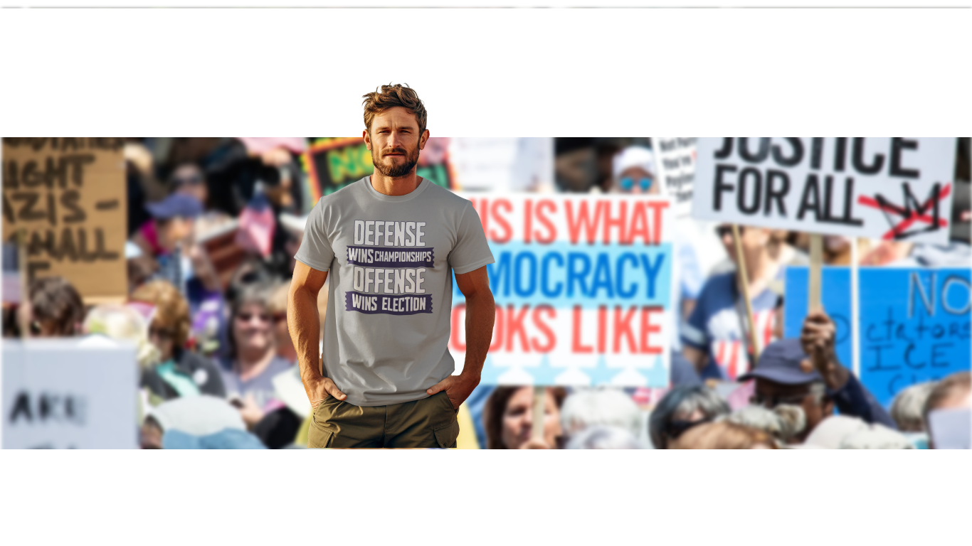 Man wearing a t-shirt with text at a protest rally with various signs in the background